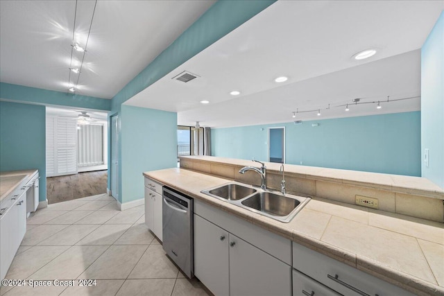 kitchen featuring stainless steel dishwasher, white cabinets, track lighting, light tile patterned floors, and sink