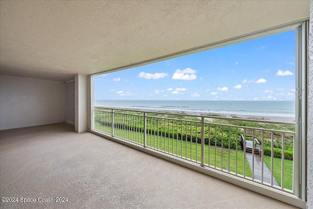 balcony featuring a view of the beach and a water view