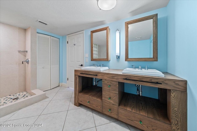 bathroom with a textured ceiling, a tile shower, vanity, and tile patterned floors