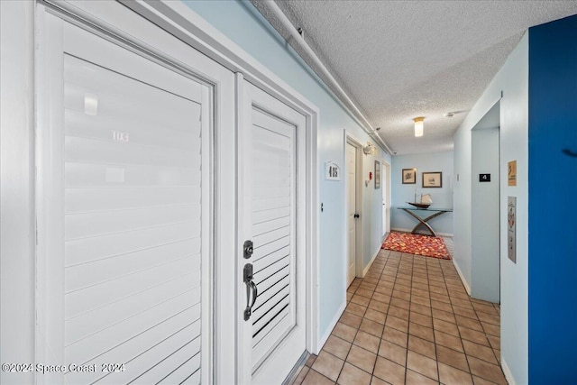 hallway featuring a textured ceiling and light tile patterned floors