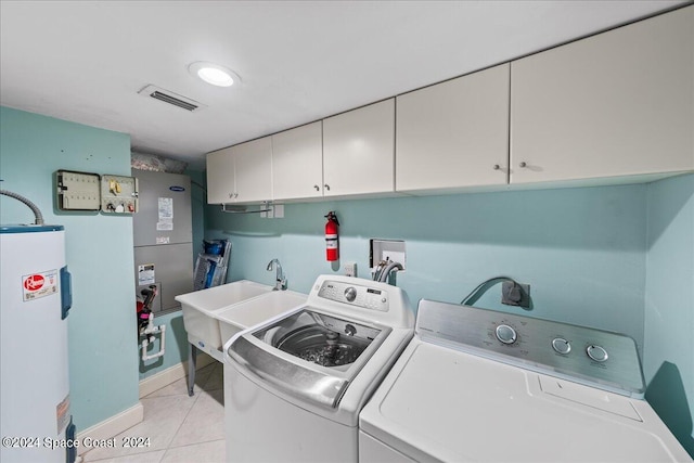 clothes washing area featuring light tile patterned flooring, electric water heater, cabinets, and washer and dryer