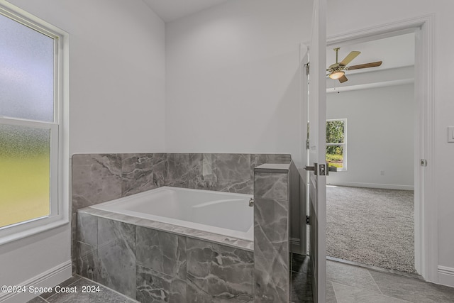 bathroom with ceiling fan, tile patterned flooring, plenty of natural light, and a relaxing tiled tub