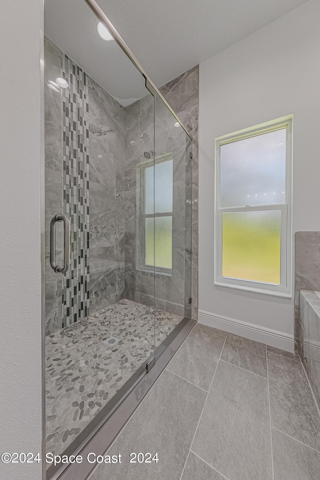 bathroom with a shower with door and tile patterned floors