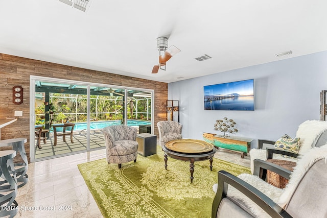 living room with ceiling fan and wooden walls