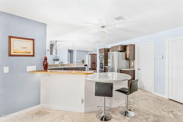 kitchen with a breakfast bar area, stainless steel appliances, kitchen peninsula, and pendant lighting