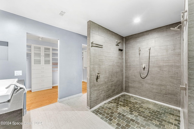 bathroom featuring vanity, a tile shower, and wood-type flooring