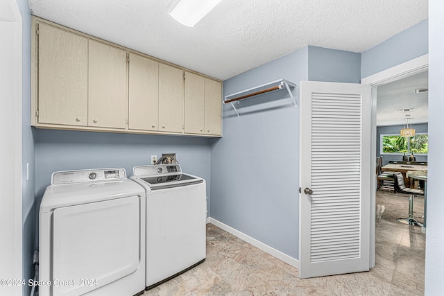 laundry area featuring a textured ceiling, cabinets, and washing machine and dryer