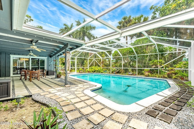 view of swimming pool featuring glass enclosure, ceiling fan, and a patio