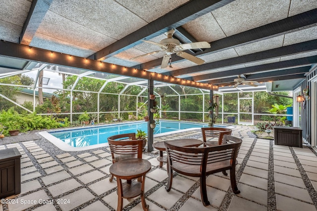 view of pool with glass enclosure, a patio, and ceiling fan