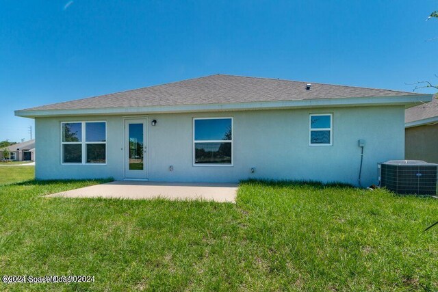 rear view of property featuring a patio area, central air condition unit, and a yard