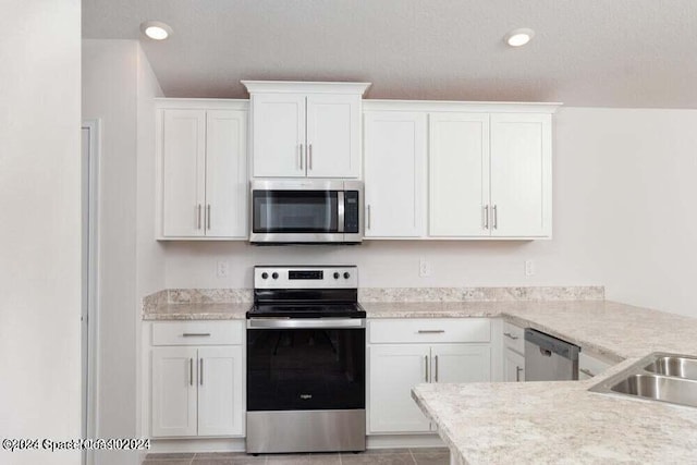 kitchen with light tile patterned flooring, stainless steel appliances, a textured ceiling, and white cabinets