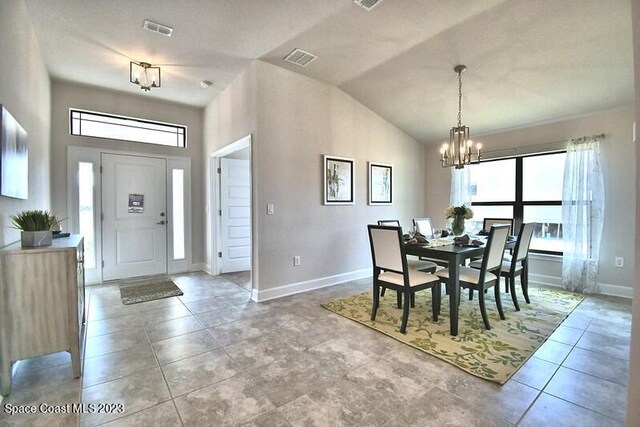 dining room featuring tile patterned floors, lofted ceiling, and a chandelier