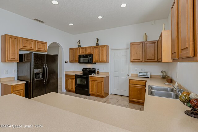 kitchen with light tile patterned floors, sink, and black appliances