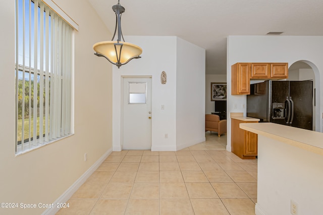 kitchen featuring hanging light fixtures, fridge, and light tile patterned floors