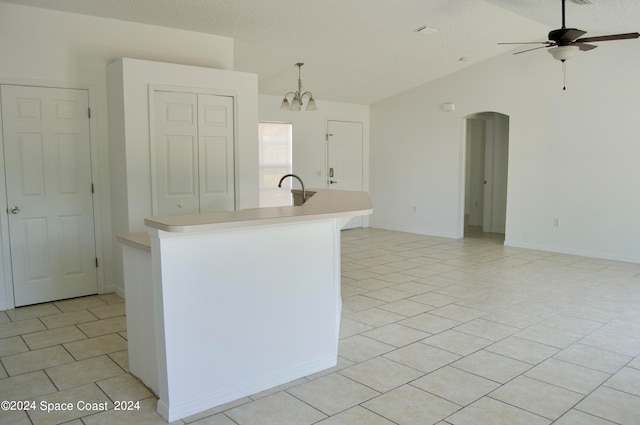 kitchen featuring vaulted ceiling, a center island with sink, light tile patterned floors, ceiling fan, and hanging light fixtures