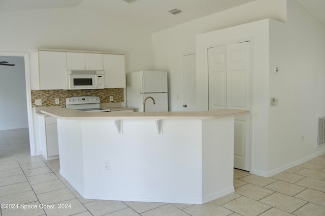 kitchen featuring decorative backsplash, an island with sink, vaulted ceiling, light tile patterned flooring, and white appliances