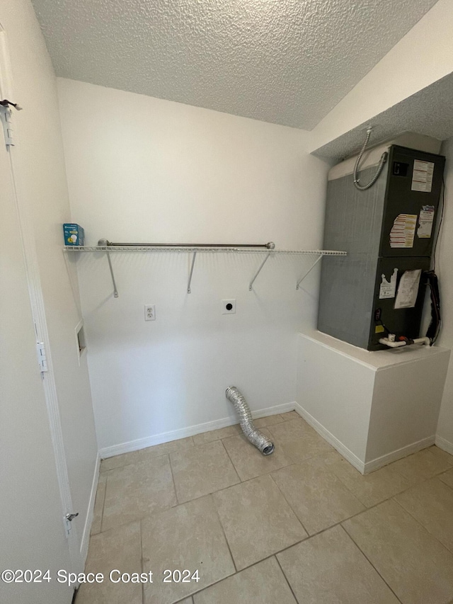 washroom featuring light tile patterned flooring, electric dryer hookup, a textured ceiling, and heating unit