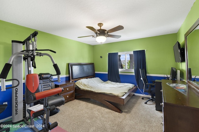 bedroom featuring light carpet, ceiling fan, a textured ceiling, and a wainscoted wall