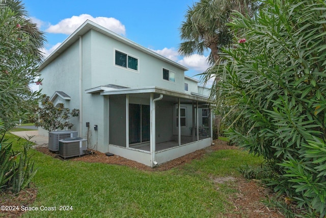 back of property featuring a sunroom, stucco siding, a yard, and central air condition unit