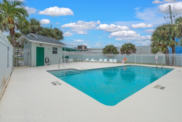 community pool with a patio area and fence