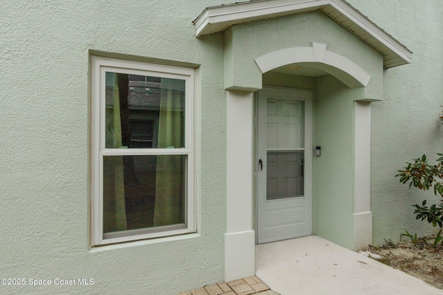 doorway to property featuring stucco siding