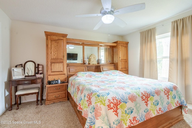 bedroom with light colored carpet, ceiling fan, and baseboards