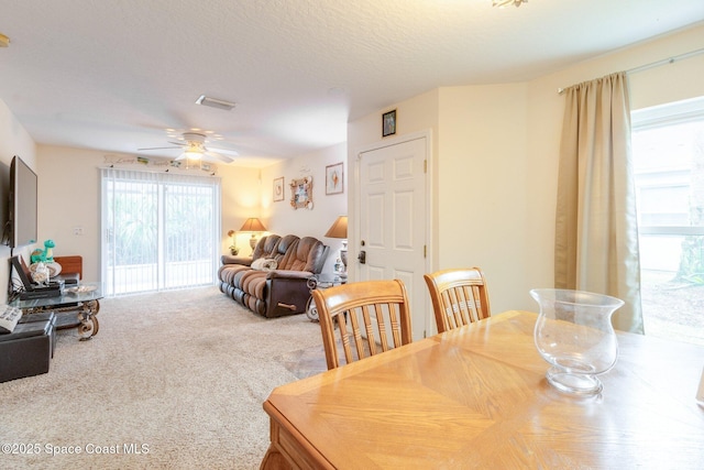 carpeted dining space featuring a textured ceiling, ceiling fan, and visible vents