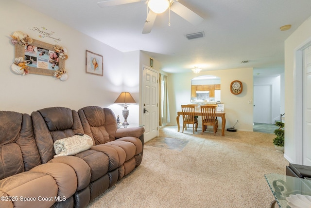 living area with visible vents, ceiling fan, light carpet, and baseboards