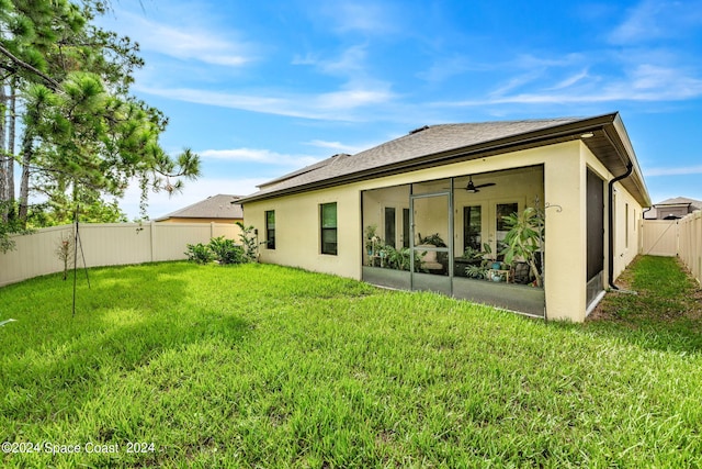 rear view of house with a lawn and ceiling fan