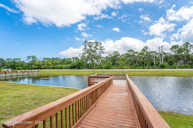 view of dock with a lawn and a water view