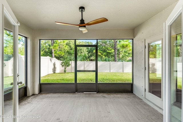 unfurnished sunroom featuring ceiling fan and plenty of natural light