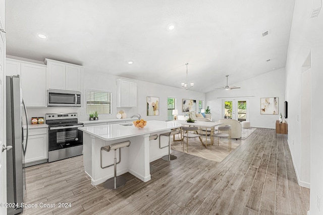 kitchen featuring light hardwood / wood-style floors, white cabinets, a kitchen island, stainless steel appliances, and lofted ceiling