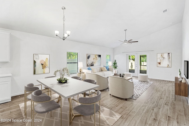 interior space with ceiling fan with notable chandelier, light hardwood / wood-style flooring, plenty of natural light, and vaulted ceiling