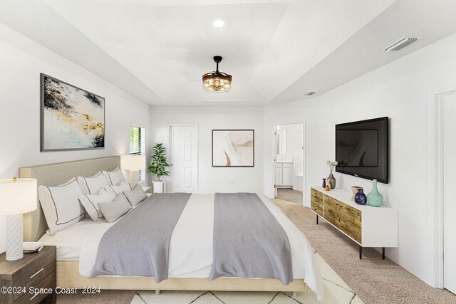 bedroom with light colored carpet and ensuite bathroom