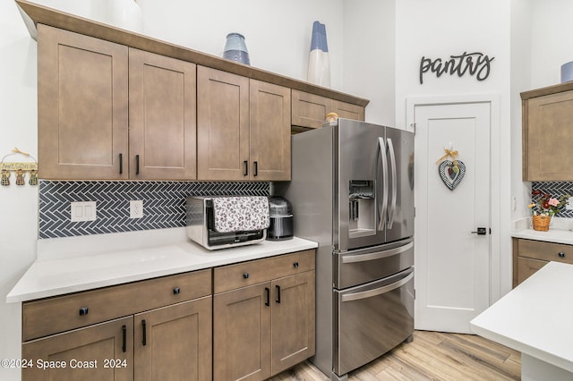 kitchen with stainless steel fridge, backsplash, and light hardwood / wood-style flooring