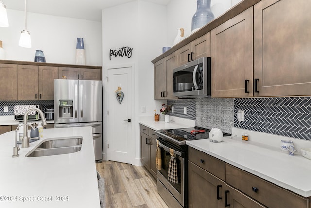 kitchen featuring backsplash, light hardwood / wood-style flooring, stainless steel appliances, sink, and pendant lighting