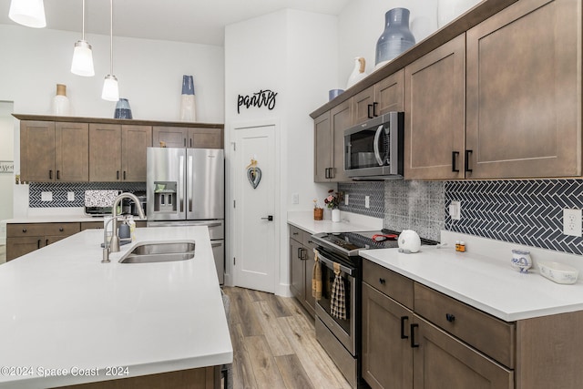 kitchen featuring appliances with stainless steel finishes, sink, decorative backsplash, and light hardwood / wood-style floors