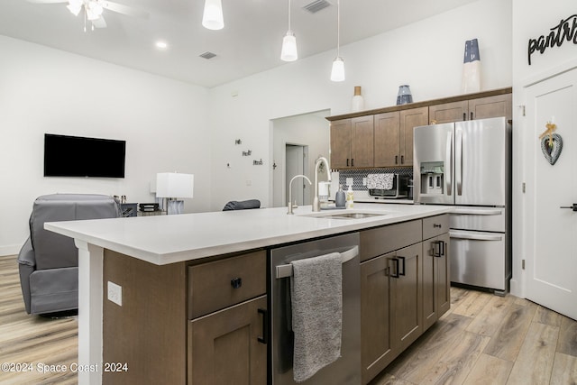 kitchen featuring a kitchen island with sink, appliances with stainless steel finishes, light hardwood / wood-style flooring, and sink