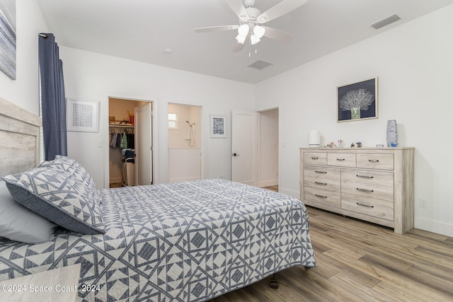 bedroom with a closet, ceiling fan, a spacious closet, and hardwood / wood-style flooring