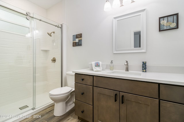 bathroom with vanity, toilet, wood-type flooring, and a shower with shower door