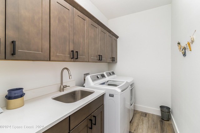 laundry area featuring light wood-type flooring, washer and clothes dryer, cabinets, and sink