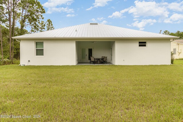 back of property with a lawn and a patio area