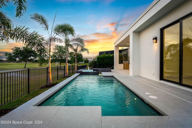 pool at dusk featuring a patio area