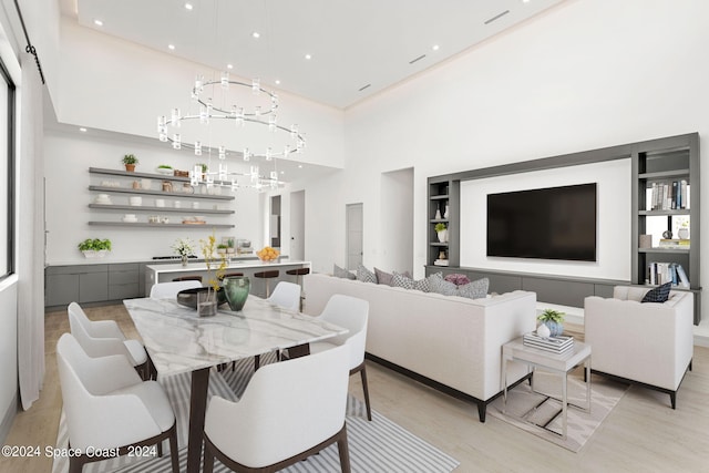 dining space with a towering ceiling, light wood-type flooring, and a chandelier