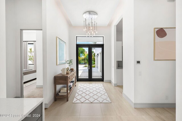 entrance foyer with light tile patterned floors, plenty of natural light, a notable chandelier, and french doors