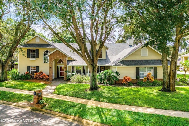 1150 Old Parsonage Dr, Merritt Island, FL 32952 - traditional-style home with a front lawn, roof with shingles, a chimney, and brick siding