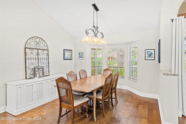 dining space featuring hardwood / wood-style floors, high vaulted ceiling, and an inviting chandelier