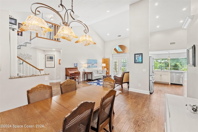 dining space with french doors, light hardwood / wood-style floors, high vaulted ceiling, and a healthy amount of sunlight