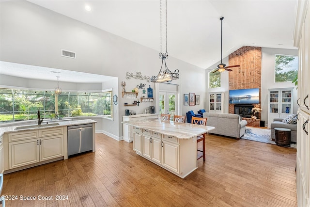 kitchen with dishwasher, a center island, a kitchen breakfast bar, high vaulted ceiling, and pendant lighting