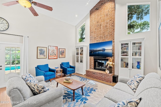 living room with a fireplace, a wealth of natural light, light hardwood / wood-style flooring, and high vaulted ceiling